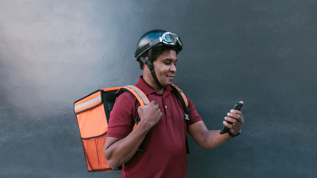 Un livreur équipé d'un casque consulte une application mobile sur mesure dans le Tarn sur son smartphone.