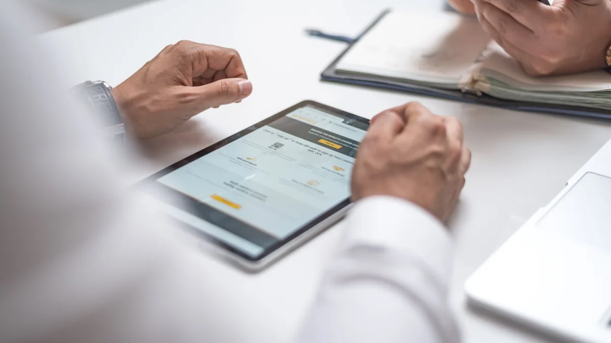 Mains de professionnels autour d'une table utilisant une tablette avec interface applicative et un téléphone portable pour connecter une application à ses logiciels à Albi.