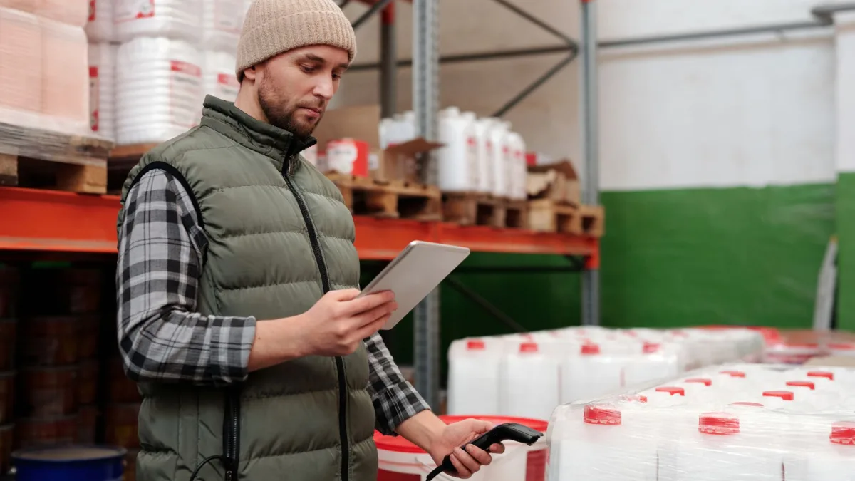 Un agent d'entrepôt utilisant un scanner code-barres et une tablette pour optimiser la gestion de stock à Perpignan.