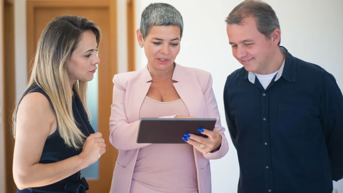 Une professionnelle montre le contenu d'une tablette tactile à deux clients pour présenter un portail client à Perpignan, illustration d'un article du blog d'EPREYN, développeur d'applications à Perpignan
